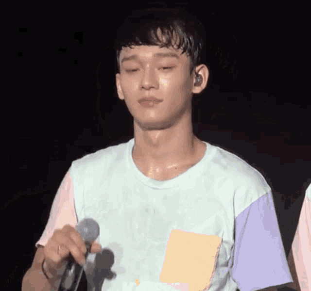a young man is holding a microphone with his eyes closed and sweating .