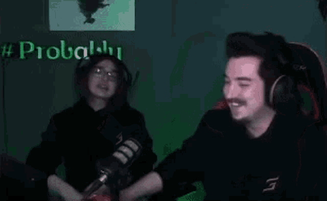 a man and a woman are sitting in front of a microphone . the man is wearing headphones .