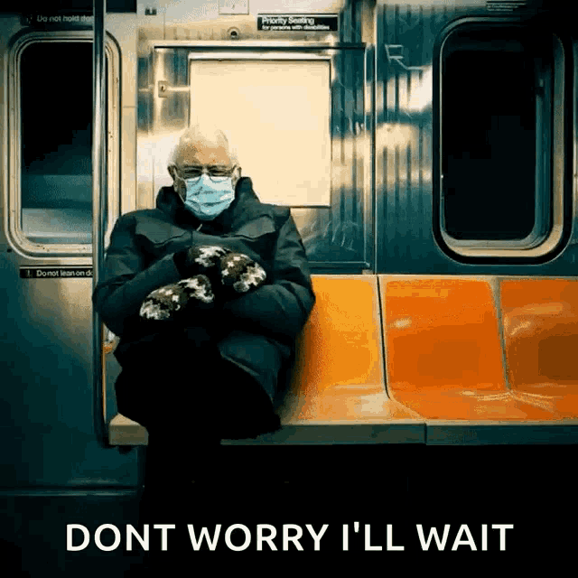 a man wearing a mask and mittens sits on a train with the words " dont worry i ll wait "