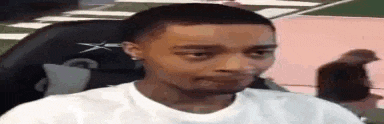a man in a white shirt is sitting in a chair making a funny face .