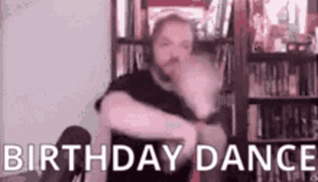 a man is dancing in front of a bookshelf in a room with the words `` birthday dance '' .