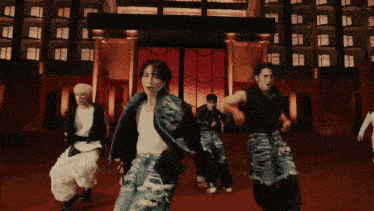 a group of young men are dancing in front of a large building