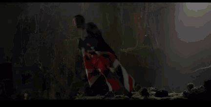a group of people are standing around a person laying on the ground in a cave .