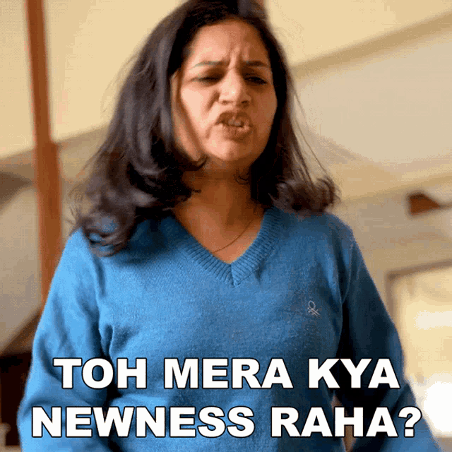 a woman in a blue sweater is making a funny face and the caption says " toh mera kya newness raha "