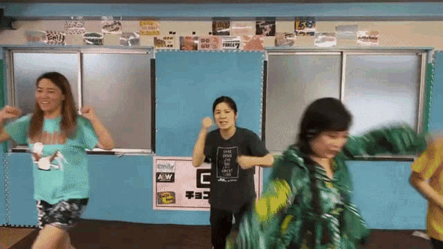 a group of women are dancing in a room with a sign that says aow on it