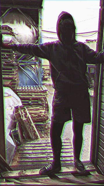 a person in a hoodie and shorts stands in a doorway