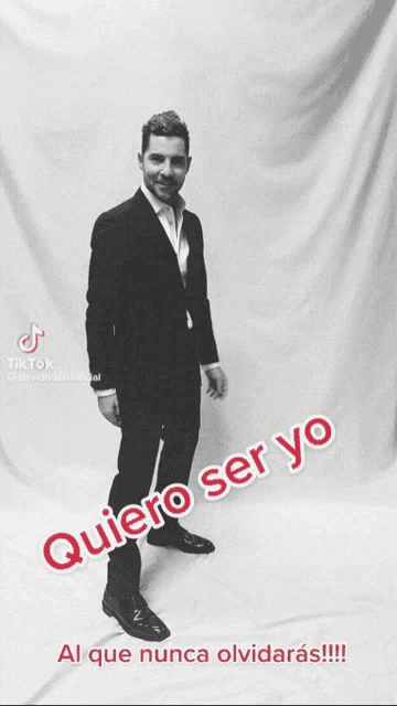 a man in a suit stands in front of a white curtain with the words quiero ser yo written on it