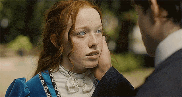 a man is touching a woman 's face with his hand while they are looking at each other .