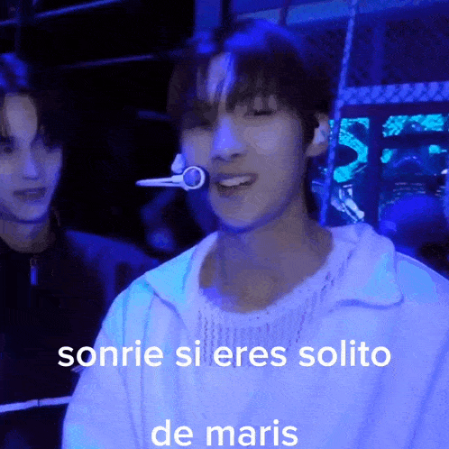 a man is smiling in front of a microphone with the words sonrie si eres solito de maris written below him
