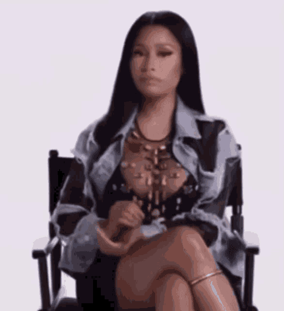 a woman is sitting in a chair with her legs crossed and looking at the camera .