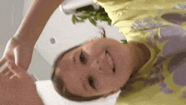 a little girl wearing a yellow shirt with a purple print on it