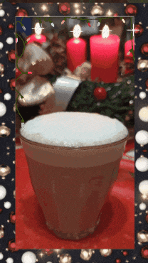 a cup of coffee with a christmas wreath in the background