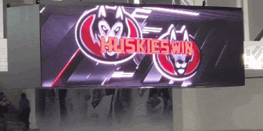 a large screen displays the huskies win logo on it