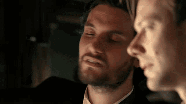 two men are standing next to each other in a dark room .