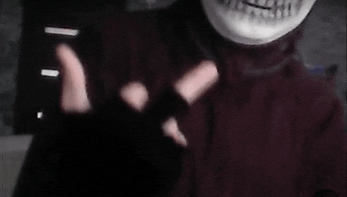 a person wearing a skeleton mask and black gloves is holding a cell phone .