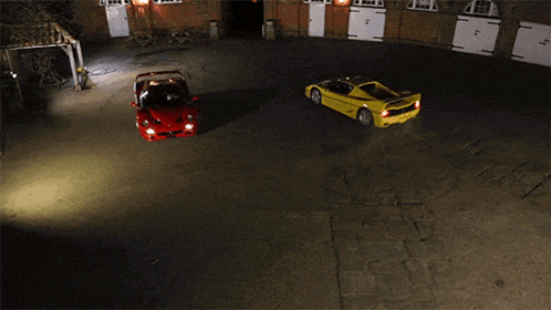 a red sports car and a yellow sports car are driving in a parking lot