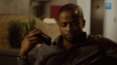 a man is sitting on a couch looking at his phone .