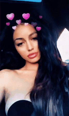 a woman with hearts on her head takes a selfie in a car