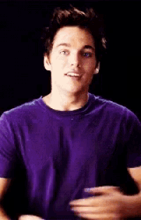 a young man in a purple shirt is smiling with his hands on his chest