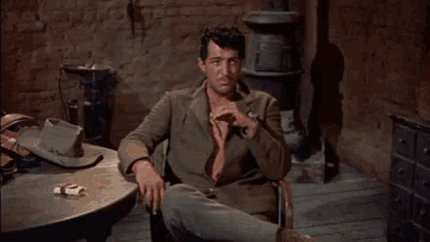 a man sits at a table with a cigarette and a hat on it