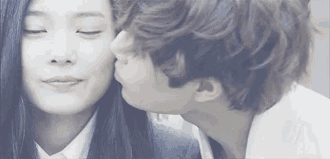 a man is kissing a woman on the cheek in a close up .