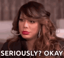 a woman is making a funny face and says `` seriously ? okay '' while wearing hoop earrings .