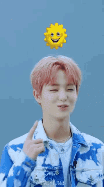 a young man with pink hair is smiling while wearing a blue and white jacket .