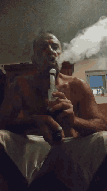 a man without a shirt is smoking a pipe with smoke coming out of his mouth