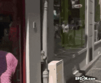 a woman in a pink and white striped shirt is standing in front of a building .