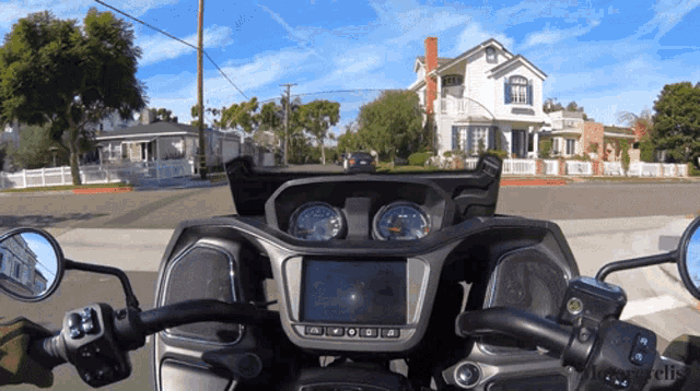 a motorcycle is driving down a residential street with a house in the background