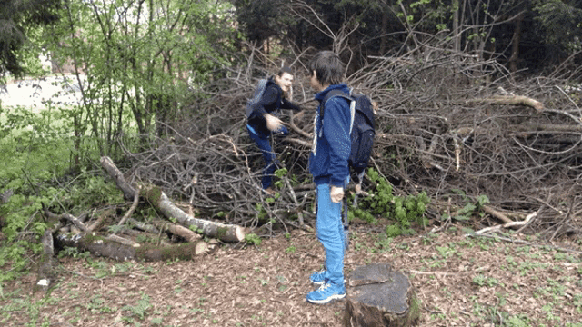 a boy with a backpack is standing next to a pile of wood