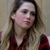 a woman wearing a red and black plaid shirt is looking at the camera .