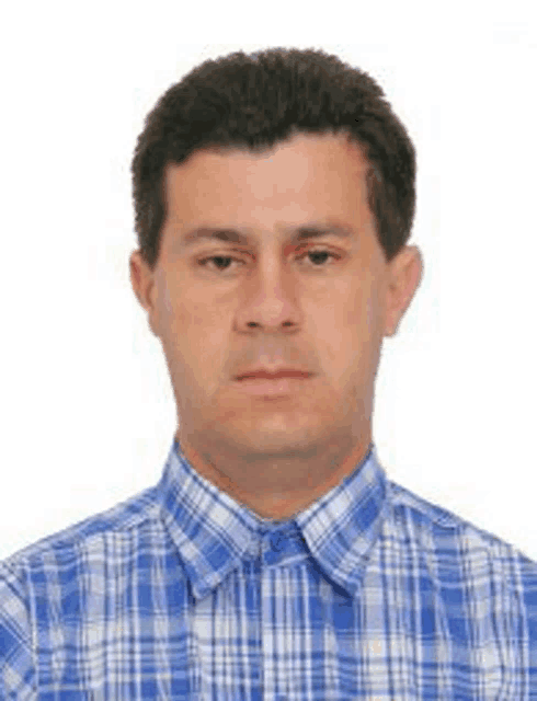 a man wearing a blue and white plaid shirt is posing for a picture .