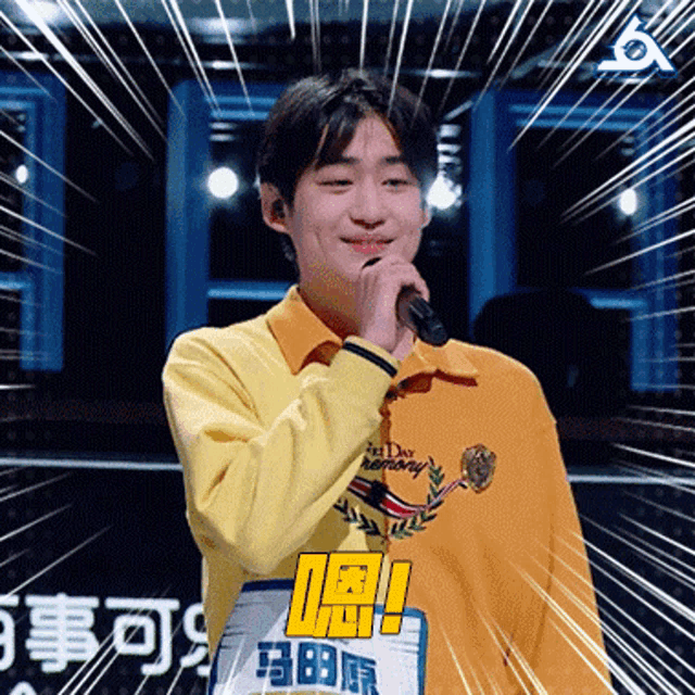a young man in a yellow shirt is singing into a microphone with the word harmony on it