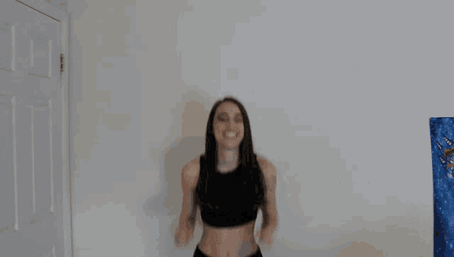 a woman in a black crop top and black shorts is jumping in the air