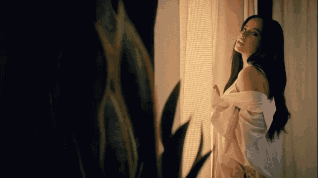 a woman is standing in front of a window with her shirt off