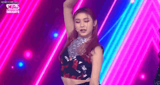 a woman is dancing on a stage in front of a neon light .
