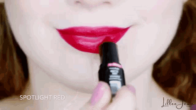 a close up of a woman applying red lipstick to her lips