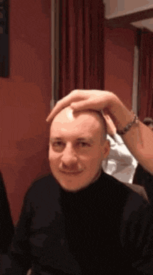 a man with a mustache is getting his head shaved by another man .