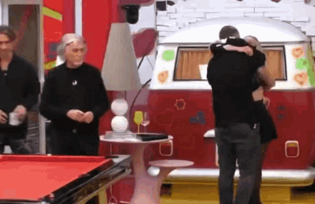 a man is hugging a woman in front of a red van