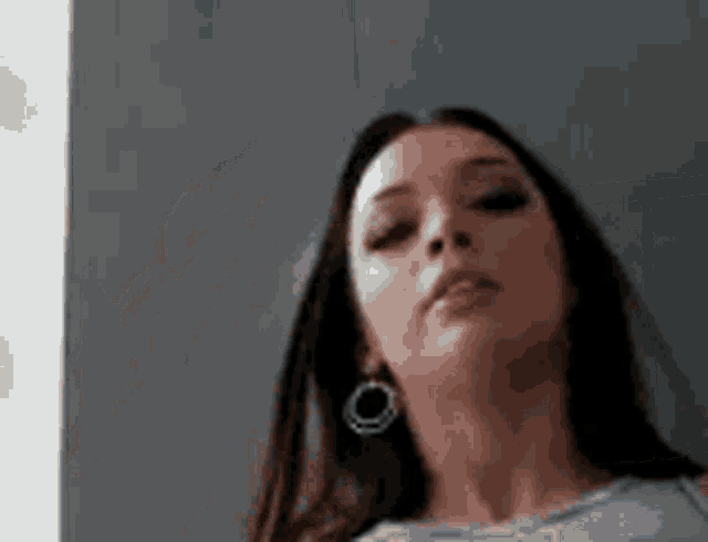 a woman wearing hoop earrings is looking at the camera with a serious look on her face .