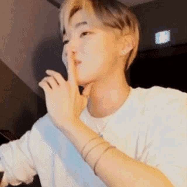 a young man is holding his finger to his mouth and making a shhh sign .