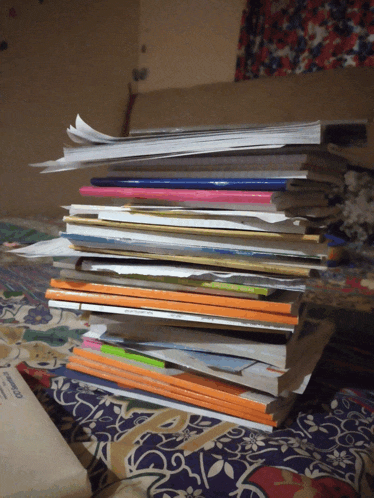 a stack of books on a bed including one that says ' biology ' on the spine
