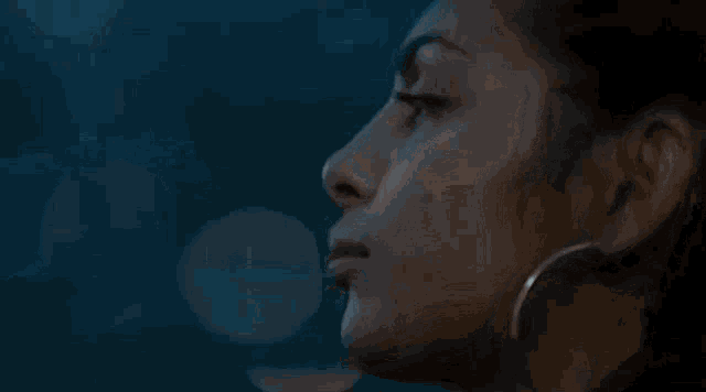 a close up of a woman wearing hoop earrings and a nose ring .