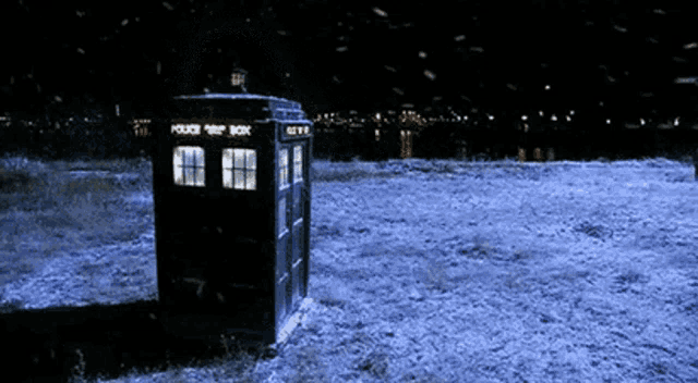 a police box is in the middle of a snowy field at night