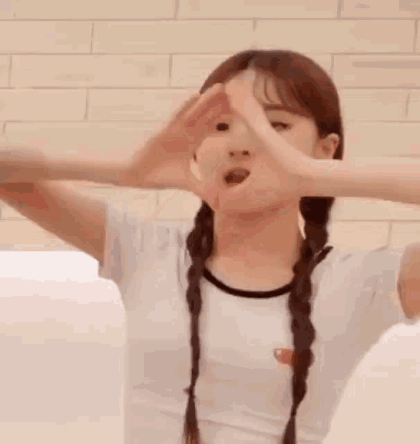 a girl is making a heart with her hands .