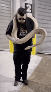 a man is holding a large snake in front of a sign that says number 2