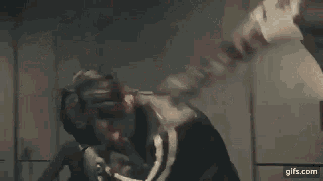 a man is laying on the floor holding a gun in a bloody room surrounded by zombies .