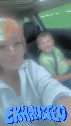 a woman and a boy are sitting in a car with exhausted written in blue