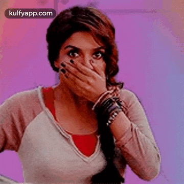 a woman is covering her mouth with her hand and making a funny face .